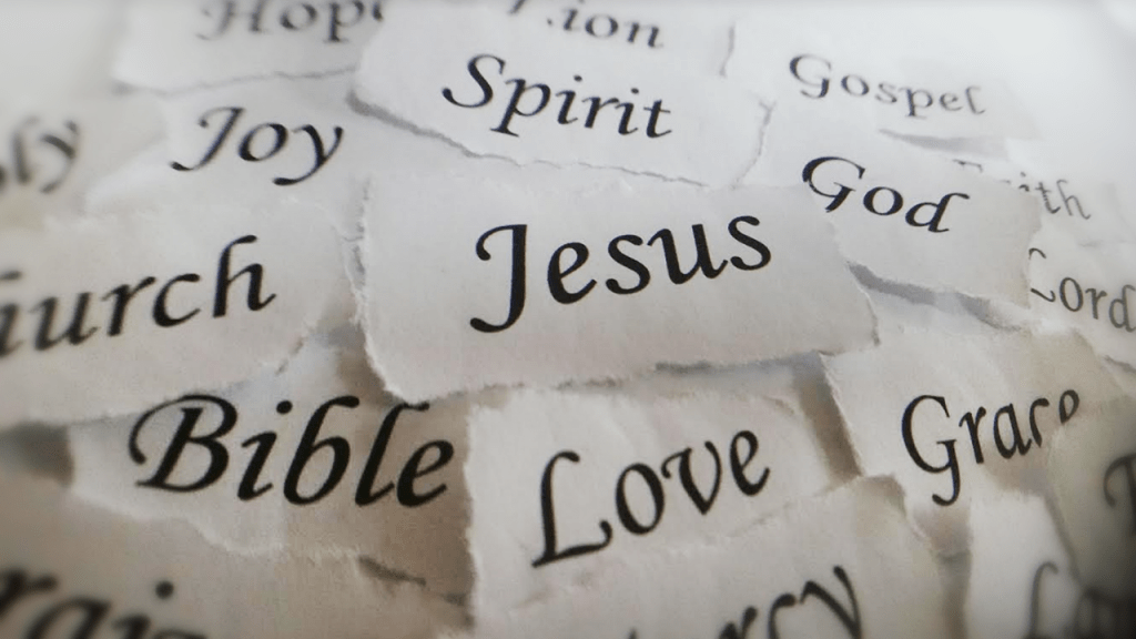 A collection of torn paper pieces with words related to Christianity, including 'Jesus', 'Bible', 'Love', 'Joy', 'Spirit', and others, arranged in a visually appealing manner.