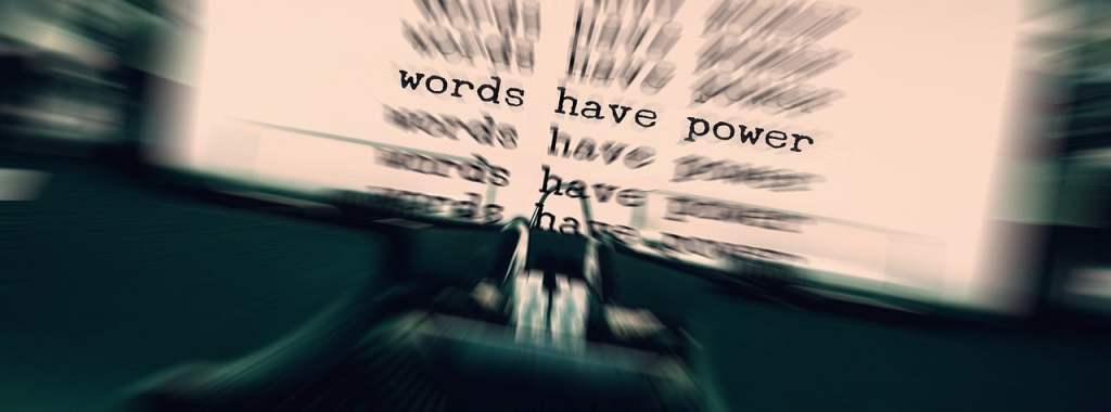 A blurred image of a typewriter with the words 'words have power' repeatedly visible on the paper.