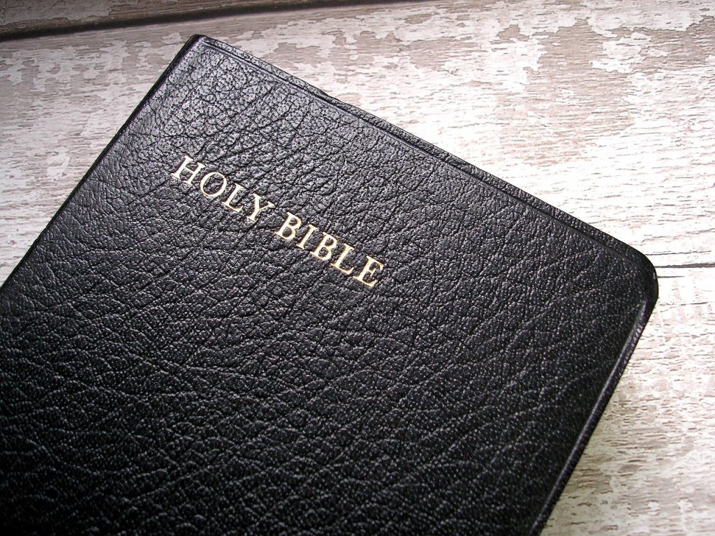 Close-up of a black leather-bound Bible with the words 'HOLY BIBLE' embossed in gold on the cover.