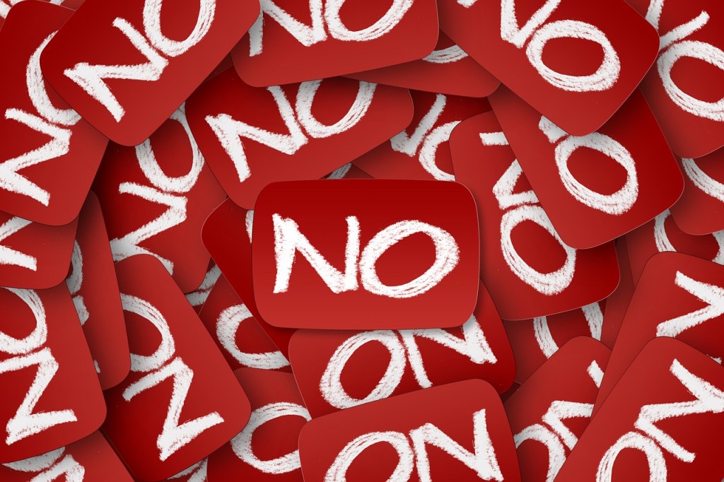 A collage of red signs with the word 'NO' written in white chalk-like text, symbolizing the message of setting boundaries and saying no.