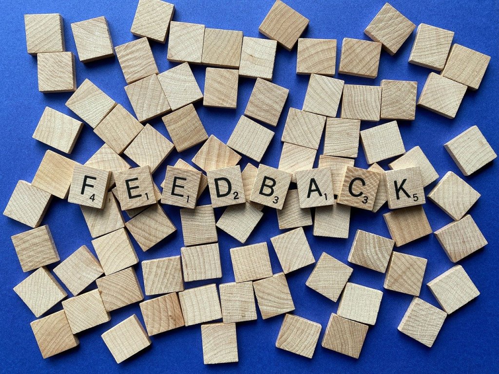 Wooden letter tiles arranged to spell 'FEEDBACK' against a blue background.
