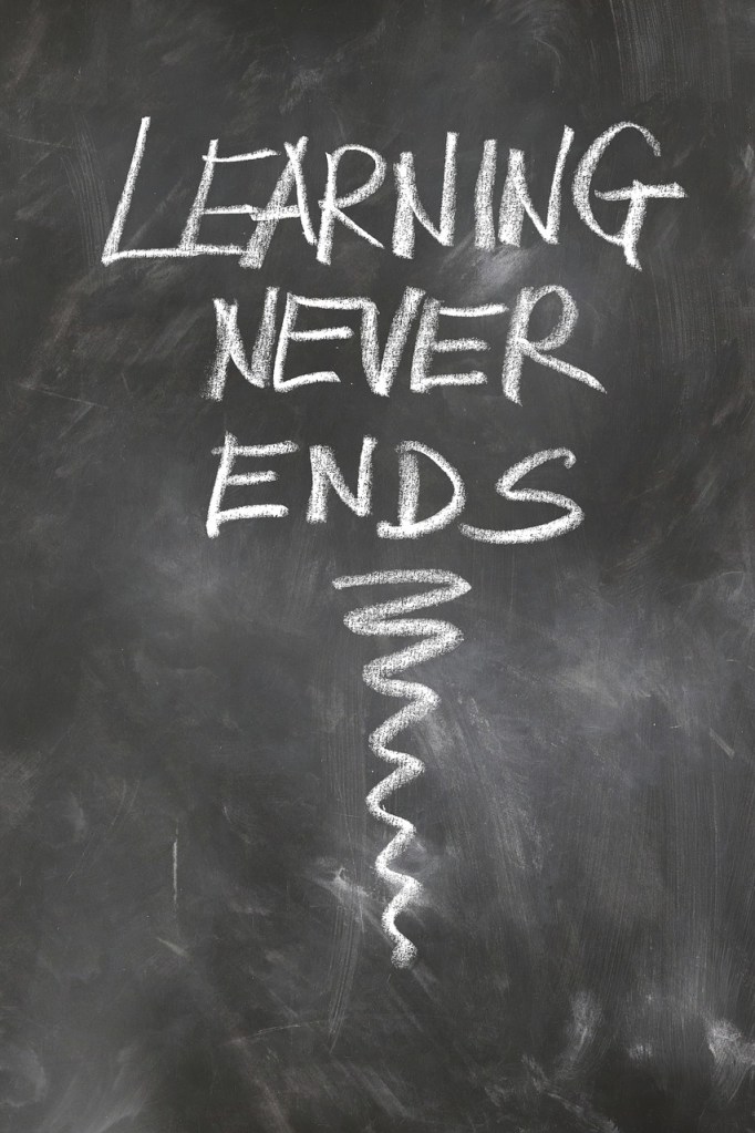 A black chalkboard with the phrase "LEARNING NEVER ENDS" written in white chalk.