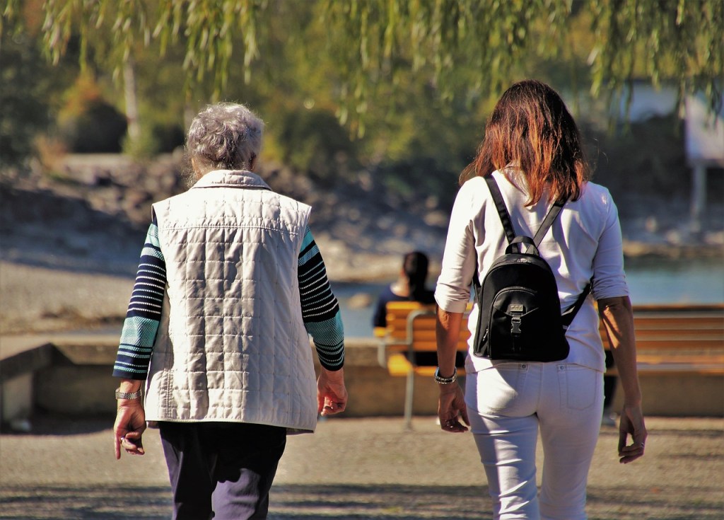 A young woman and an older woman walking together outdoors, symbolizing mentorship and intergenerational connection.