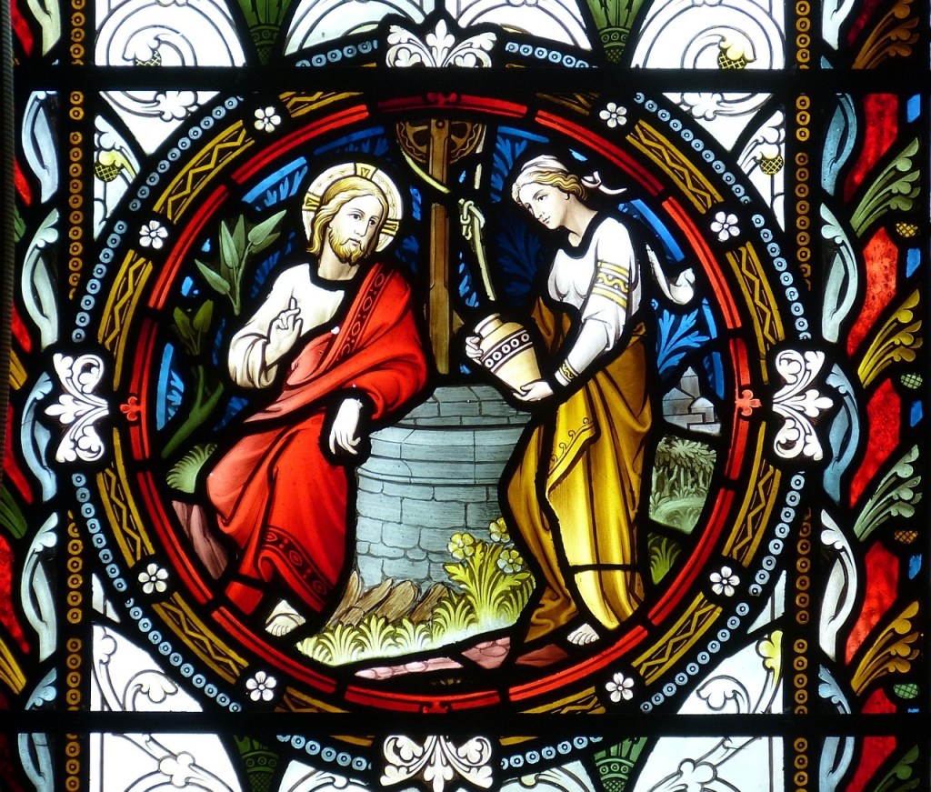 Stained glass artwork depicting Jesus speaking with a woman at a well in a natural setting.