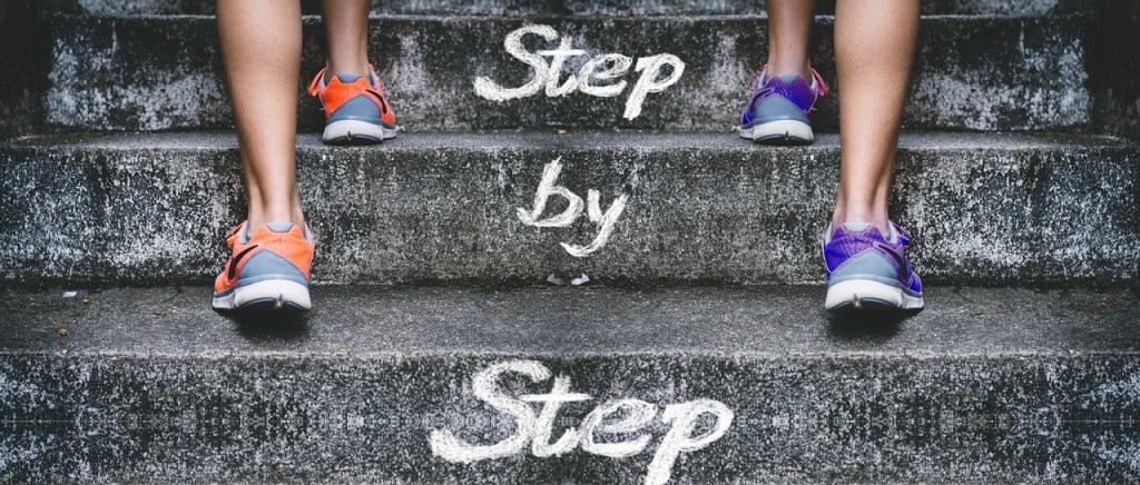 A person walking up stairs in colorful sneakers, with the phrase 'Step by Step' written in a playful font.