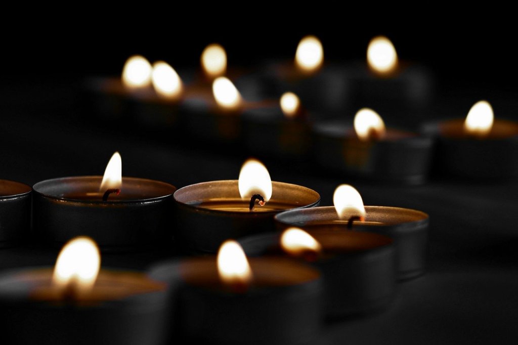 Close-up of multiple flickering tea light candles against a dark background, creating a serene and contemplative atmosphere.