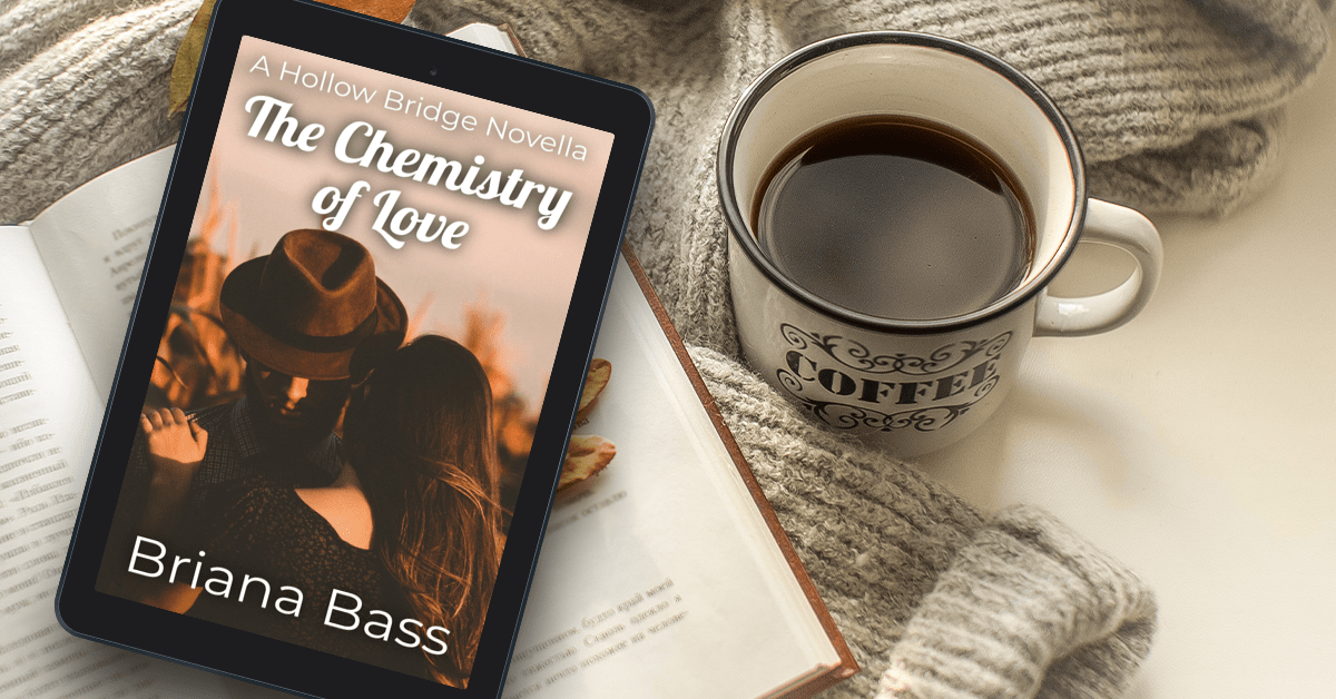 A digital tablet displaying the cover of 'The Chemistry of Love' by Briana Bass, resting on an open book next to a coffee cup on a cozy knit blanket.