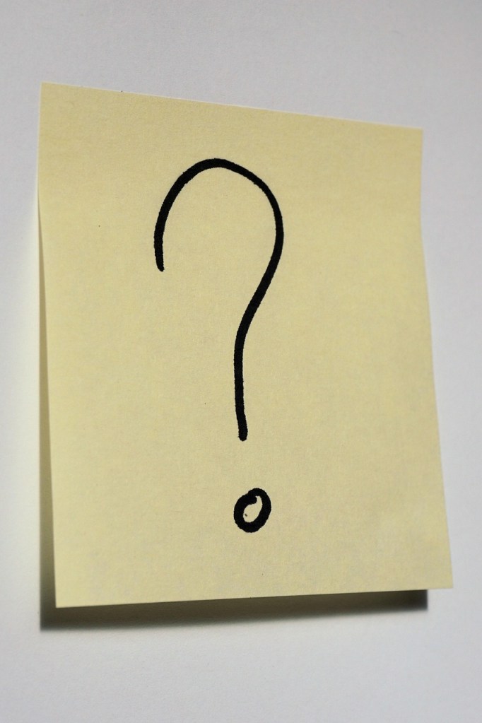 A yellow sticky note with a black question mark drawn on it.